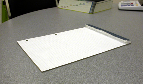 Photograph of a pad of paper with one sheet left.